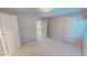 Spacious bedroom with neutral carpeting, featuring two doors, and a light-filled window at 98 Lochridge Dr, Roxboro, NC 27573