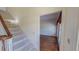 Bright hallway featuring carpeted stairs leading up and an open doorway leading into a room with hardwood flooring at 98 Lochridge Dr, Roxboro, NC 27573
