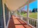 Covered front porch with brick floor, white columns, and a view of the front yard at 98 Lochridge Dr, Roxboro, NC 27573