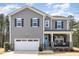 Charming two-story home featuring a front porch with stone accents and a bright blue front door at 104 Chaseford Ct, Holly Springs, NC 27540