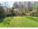 Lush green backyard with views of trees, including an Eastern Redbud in bloom, and a black fence at 11129 Bayberry Hills Dr, Raleigh, NC 27617