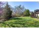 Expansive green backyard featuring mature trees, a black fence, and stairs to a deck at 11129 Bayberry Hills Dr, Raleigh, NC 27617