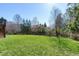 Spacious green backyard featuring mature trees and views of a black fence in a serene setting at 11129 Bayberry Hills Dr, Raleigh, NC 27617