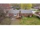 Aerial view of brick house, showcasing deck, landscaping, and mature trees in backyard at 1208 Briarcliff Rd, Burlington, NC 27215