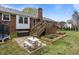 Landscaped backyard with patio, wooden deck, garden beds, and brick home at 1208 Briarcliff Rd, Burlington, NC 27215