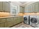 Practical laundry room with green cabinets, granite countertops, sink, and modern washer and dryer at 121 Highclere Ln, Cary, NC 27518
