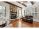 Living room with stone fireplace, wood beam ceiling, plantation shutters, hardwood floors and leather sofa at 121 Highclere Ln, Cary, NC 27518
