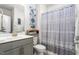 Well-lit bathroom featuring a vanity with gray cabinets, a toilet, and a shower with decorative curtain at 1415 Dalton Pl, Mebane, NC 27302