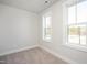 Clean empty bedroom with neutral walls and carpet, featuring bright windows to let in natural light at 146 Weavers Grove Dr, Chapel Hill, NC 27514
