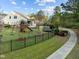 Landscaped backyard with a black fence, playset, trampoline, and a well-maintained lawn at 1527 Ingraham Dr, Apex, NC 27502