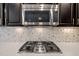 Close-up of stainless steel microwave above gas range with mosaic tile backsplash in modern kitchen at 1527 Ingraham Dr, Apex, NC 27502