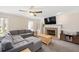 Living room boasts a brick fireplace, neutral walls, and plush gray sectional sofa under a ceiling fan at 202 Lighthouse Way, Cary, NC 27511