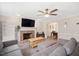 Cozy living room featuring a brick fireplace, ceiling fan and comfortable gray sectional sofa at 202 Lighthouse Way, Cary, NC 27511