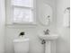 Well-lit half bathroom with a pedestal sink and toilet and natural light at 2020 Battlewood Rd, Apex, NC 27523