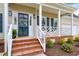 Welcoming front porch with brick steps, white railing, and a blue front door with a wreath at 2020 Battlewood Rd, Apex, NC 27523
