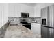 Close up on bright kitchen features granite counters, stainless appliances, and stylish mosaic tile backsplash at 2020 Battlewood Rd, Apex, NC 27523