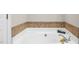 Bathroom with large white tub and decorative tile surround at 206 Herronwood Dr, Graham, NC 27253