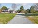 Long gravel driveway leading to a well-maintained home with a large yard and mature trees at 206 Herronwood Dr, Graham, NC 27253