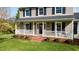 Inviting front porch featuring white railings, brick steps, and a decorative wreath on the front door at 206 Herronwood Dr, Graham, NC 27253
