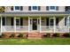 Charming front porch adorned with a festive wreath, manicured landscaping, and classic architectural details at 206 Herronwood Dr, Graham, NC 27253