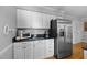 Kitchen featuring stainless steel refrigerator, sleek white cabinetry and black granite countertops at 206 Herronwood Dr, Graham, NC 27253