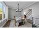 Bright dining room features hardwood floors, a modern chandelier, and a view to the adjacent staircase at 207 Grand Ave, Raleigh, NC 27606