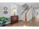 The entryway features hardwood floors, a staircase, decorative chest, natural light, and gray walls at 207 Grand Ave, Raleigh, NC 27606