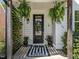 Charming front door adorned with a wreath, potted plants, and hanging ferns exudes a warm and inviting ambiance at 207 Grand Ave, Raleigh, NC 27606