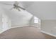 A carpeted attic area, featuring neutral walls, a ceiling fan, and a window, providing a versatile space at 213 Billingrath Turn Ln, Cary, NC 27519