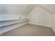 A carpeted attic space with built-in shelving and a doorway, providing ample storage and organization at 213 Billingrath Turn Ln, Cary, NC 27519