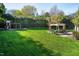 A landscaped backyard with a lush lawn, mature trees, play structure, and a patio with an outdoor dining area at 213 Billingrath Turn Ln, Cary, NC 27519