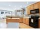 Bright kitchen featuring light wood cabinets, a black oven, a kitchen island, and wood floors at 213 Billingrath Turn Ln, Cary, NC 27519