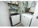 Efficient laundry room featuring modern washer and dryer, ample storage and stylish wallpaper at 2133 Persimmon Ridge Dr, Raleigh, NC 27604