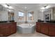 Bright bathroom featuring a large soaking tub, dual vanities with granite countertops, and tiled floors at 219 Begen St, Morrisville, NC 27560