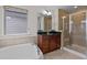 Bathroom with a large soaking tub, granite countertops, and glass-enclosed shower with tile surround at 219 Begen St, Morrisville, NC 27560