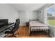 Bright bedroom features hardwood floors, a metal bed frame and a large window overlooking the backyard at 221 Walkers Way, Willow Springs, NC 27592