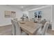 Bright dining room with wooden table, white chairs, and decorative artwork in an open floor plan at 242 Luftee Ln, Holly Springs, NC 27540