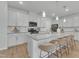 Kitchen with white cabinetry, granite countertops, an island with seating for four, and hardwood floors at 242 Luftee Ln, Holly Springs, NC 27540