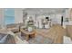 Open-concept living room with wood floors seamlessly flows into a modern kitchen and adjacent dining area at 242 Luftee Ln, Holly Springs, NC 27540
