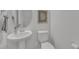 Stylish powder room with a pedestal sink, round mirror, and decorative artwork above the toilet at 242 Luftee Ln, Holly Springs, NC 27540