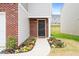 Inviting front entry with a black front door, red brick accents, and landscaping with colorful flowers at 2512 Lily Dr, Haw River, NC 27258