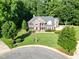 Aerial view of a brick house featuring a manicured front lawn and mature trees in a wooded setting at 2514 Mcgowan Ct, Wake Forest, NC 27587