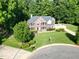 Aerial view of a brick house in a wooded area with a manicured lawn and mature trees at 2514 Mcgowan Ct, Wake Forest, NC 27587