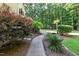 A brick pathway leading through a landscaped backyard with mature trees. A natural setting at 2514 Mcgowan Ct, Wake Forest, NC 27587