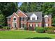 Stately brick home featuring a manicured lawn, mature trees, and a welcoming front entrance with tasteful landscaping at 2514 Mcgowan Ct, Wake Forest, NC 27587