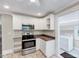 Bright kitchen with stainless steel appliances, granite counters and white cabinetry leading to laundry area at 309 W Parrish Dr, Benson, NC 27504