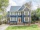 Charming two-story home featuring blue siding, white shutters, a red door, and landscaped front yard at 3100 Anderson Dr, Raleigh, NC 27609