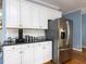 Kitchen area featuring stainless steel refrigerator, white cabinets, granite countertops, and hardwood flooring at 3100 Anderson Dr, Raleigh, NC 27609