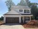 Two-story white home with black shutters, open garage, and a concrete driveway under a bright blue sky at 35 Fetterbush Way, Clayton, NC 27520
