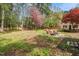 Lush backyard featuring mature trees, seating around firepit, and beautiful landscaping at 4012 Old Sturbridge Dr, Apex, NC 27539